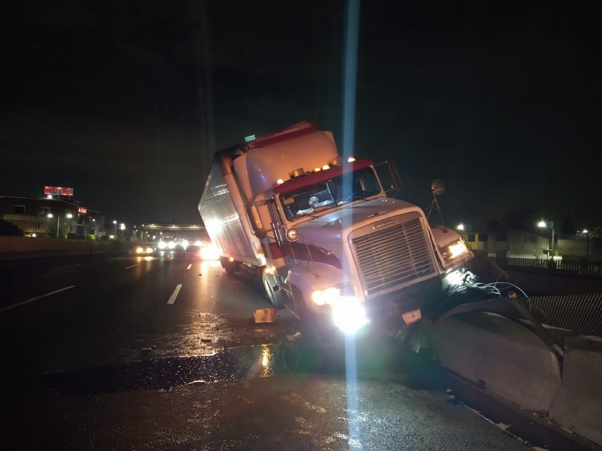 Por ir a exceso de velocidad, trailero brinca muro de contención en la México-Puebla