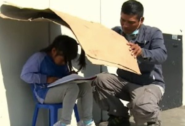 Becan a pequeñita captada estudiando en la calle bajo un trozo de cartón