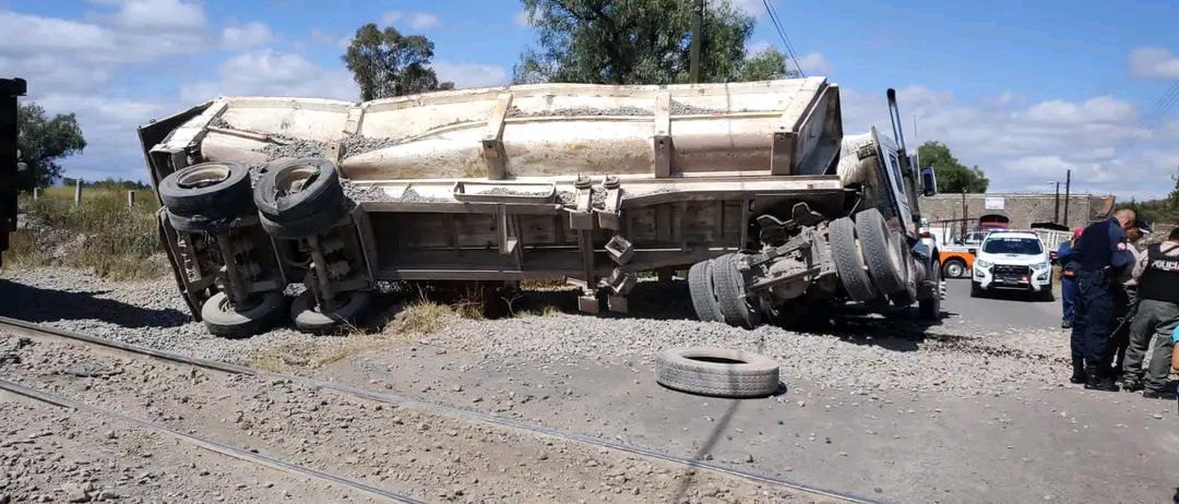 Tráiler con grava vuelca al intentar ganarle el paso al tren en Tecámac