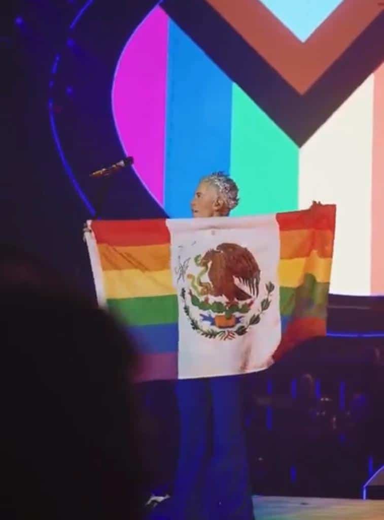 Christian Chávez muestra la bandera de México con los colores de la comunidad LGBT+ durante su actuación en un concierto de RBD