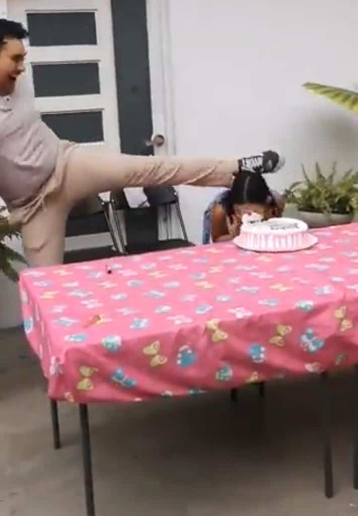 Papá da patada a niña para empujarla en pastel de cumpleaños