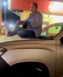 Se sube a cofre de su carro para que no se lo lleve la grúa